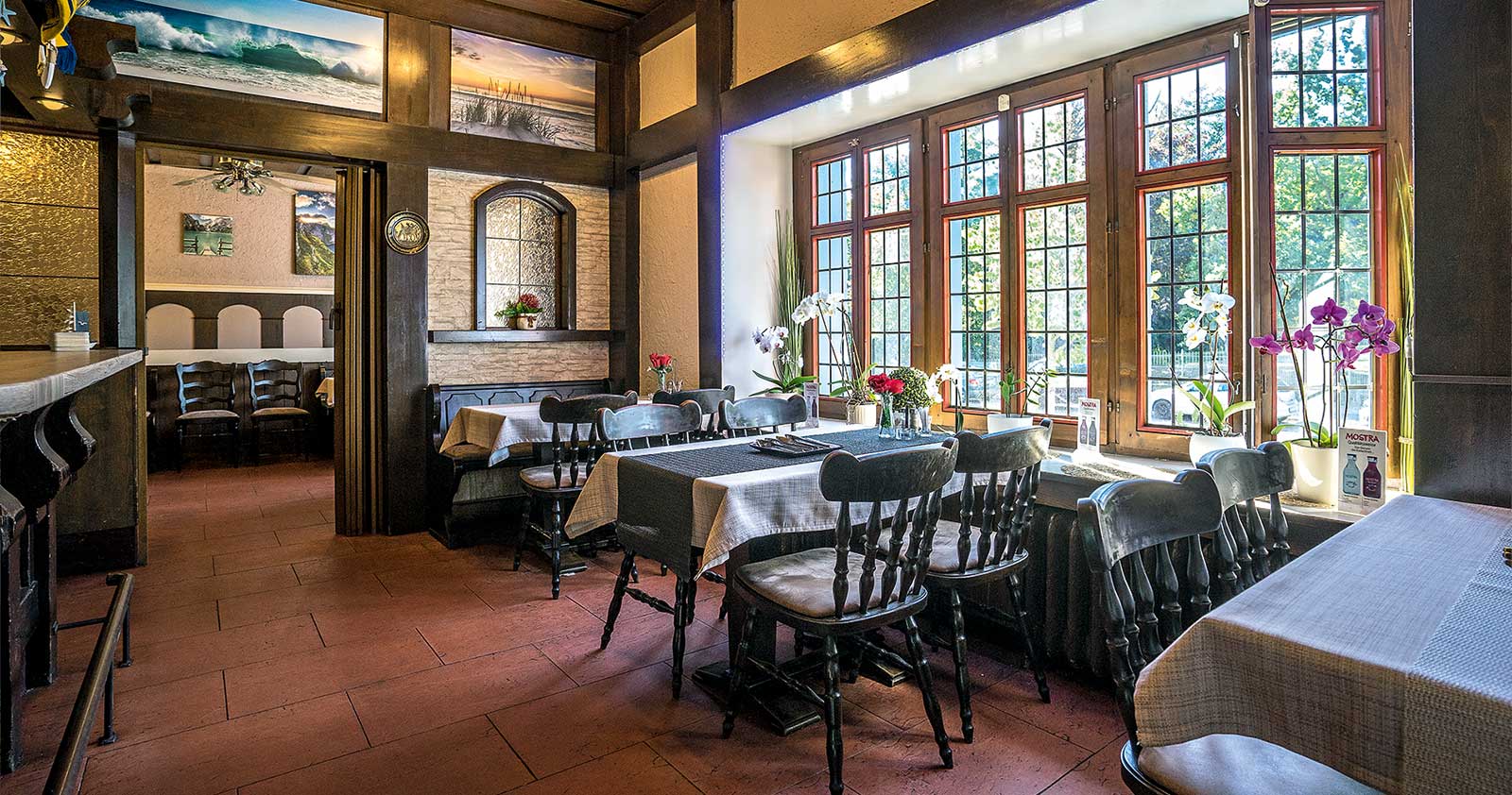 Heller Gastraum mit großer Fensterfront und eingedeckten Tischen